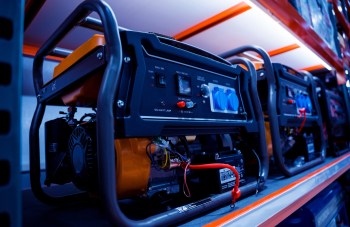 Several portable generators lined up on a shelf, featuring control panels and power outlets.
