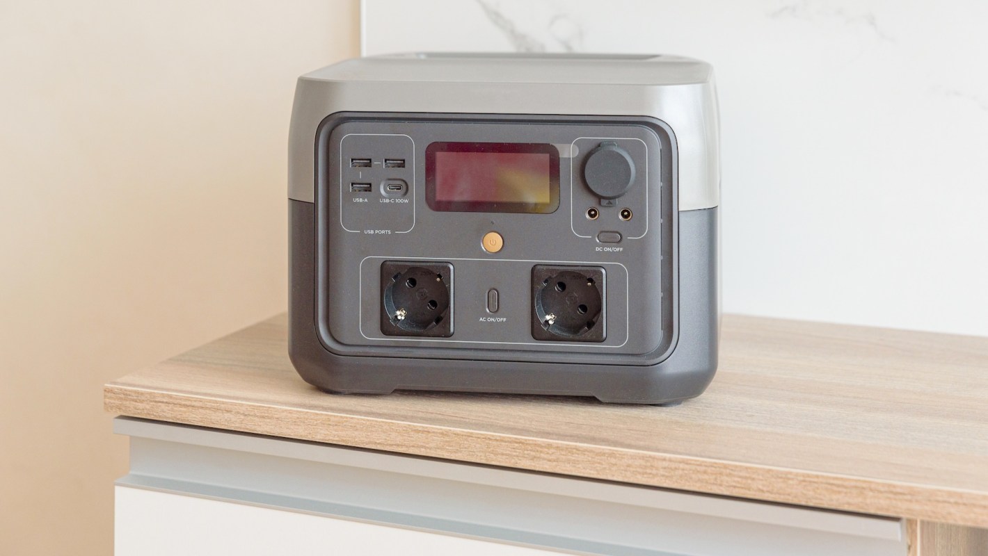 A portable power station with multiple USB and AC ports on a wooden surface.