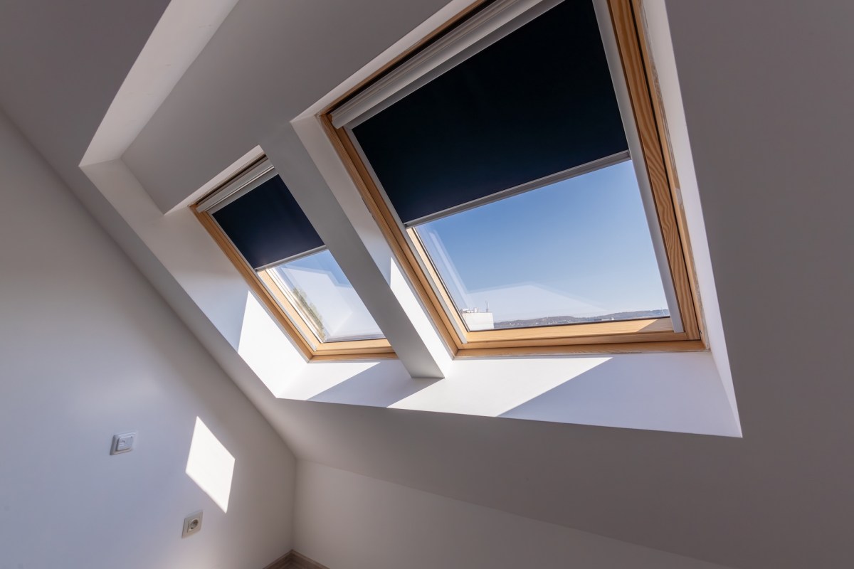 Three skylights with dark shades in a bright, minimalist room.