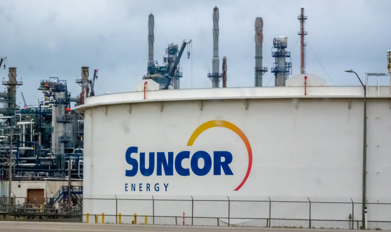 A large storage tank with the Suncor Energy logo and industrial structures in the background.