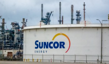 A large storage tank with the Suncor Energy logo and industrial structures in the background.