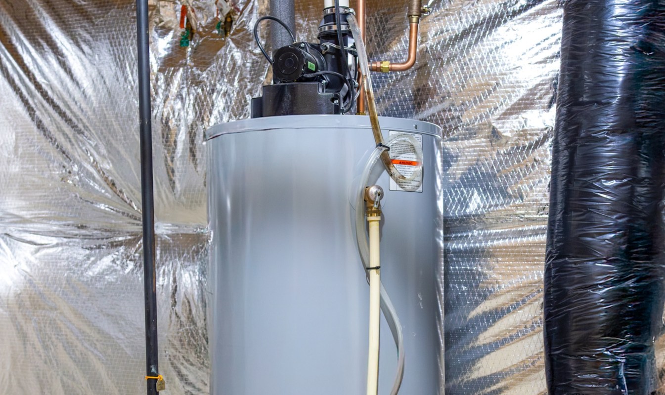 An electric water heater installed in a basement with insulated walls.