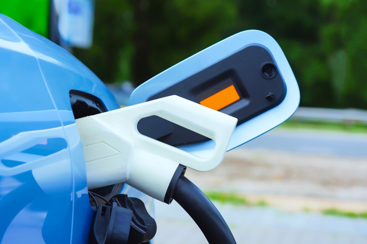 An electric vehicle charging connector is plugged into a car.