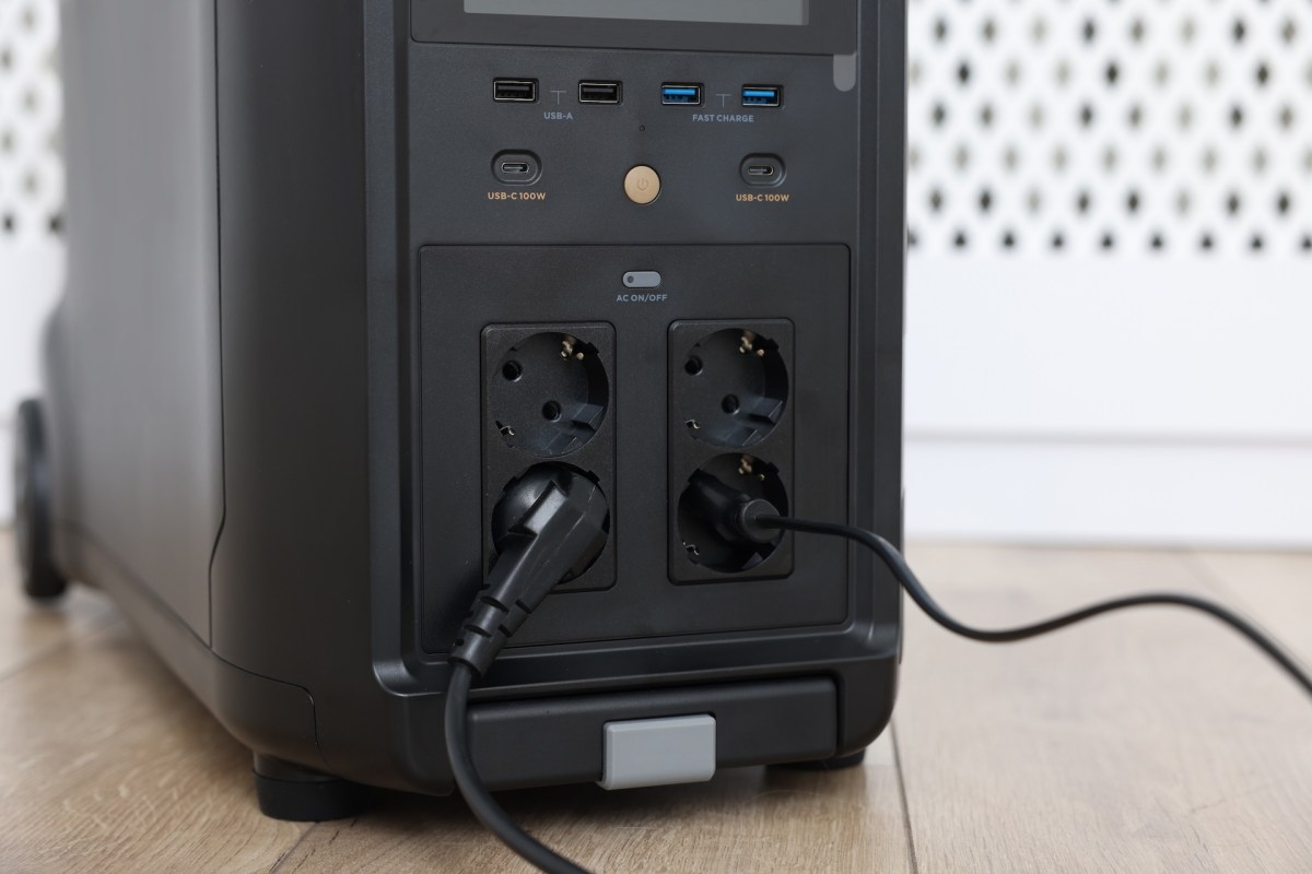 A power station with multiple ports and cables connected to it, placed on a wooden floor.