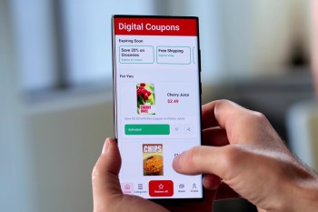 A person interacts with a smartphone displaying a digital coupon app featuring offers for groceries.
