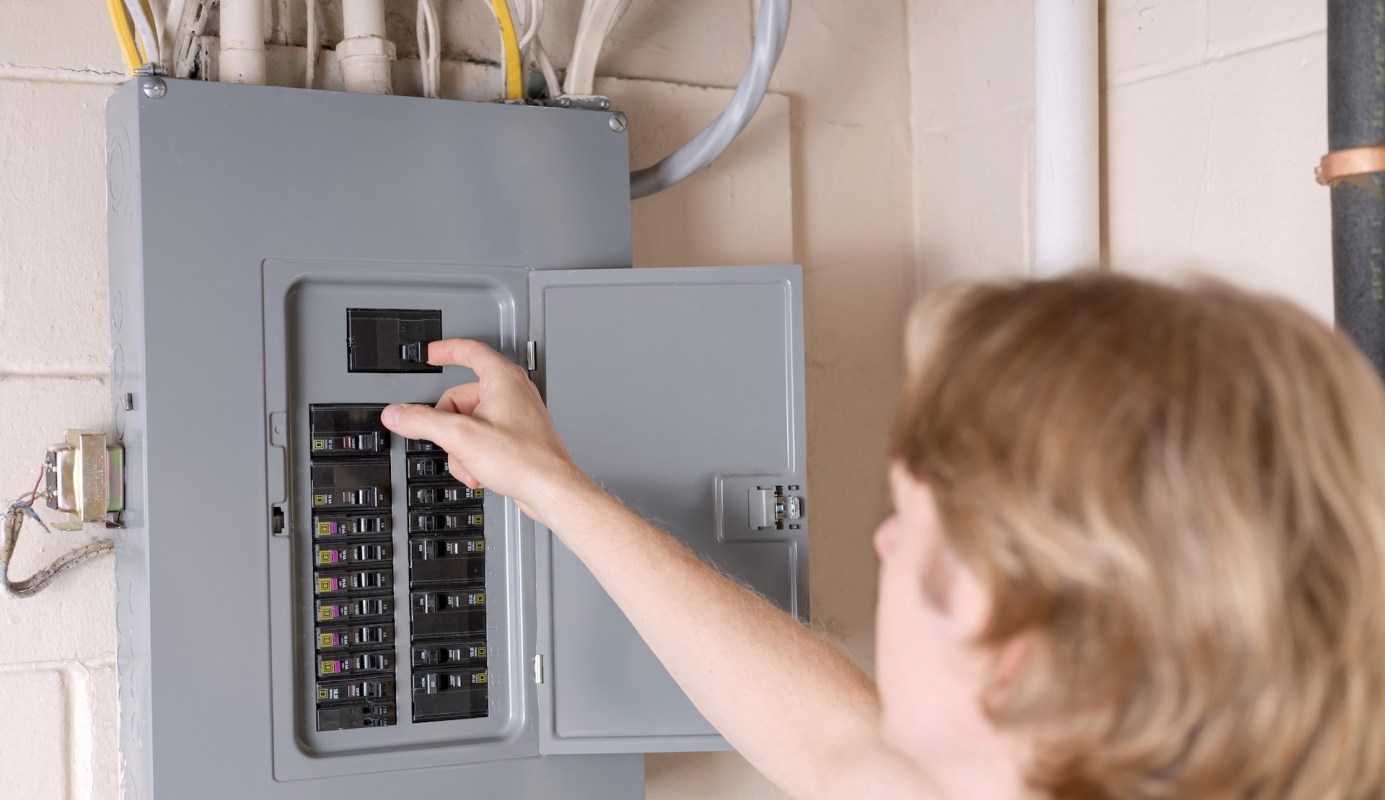 A person adjusts the power in a circuit breaker box in a gray electrical panel.