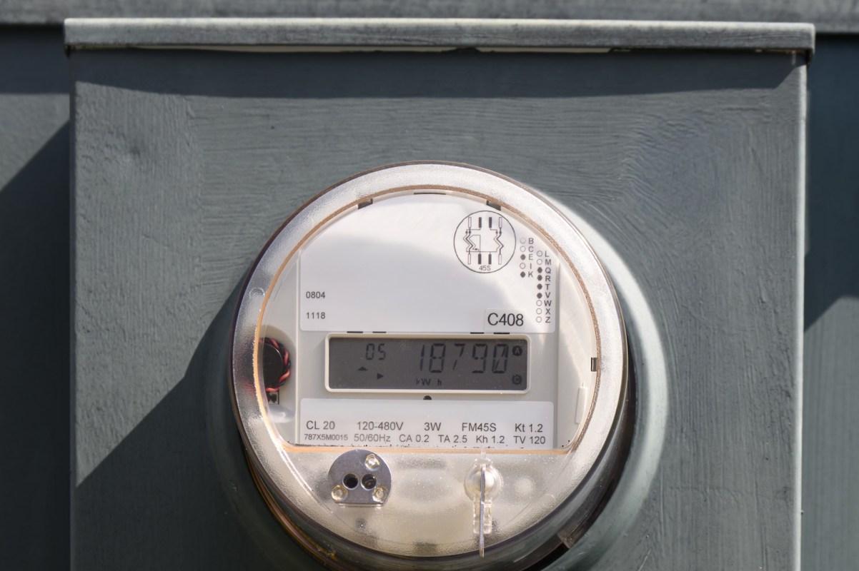 A digital electricity meter mounted on a wall, displaying usage readings.