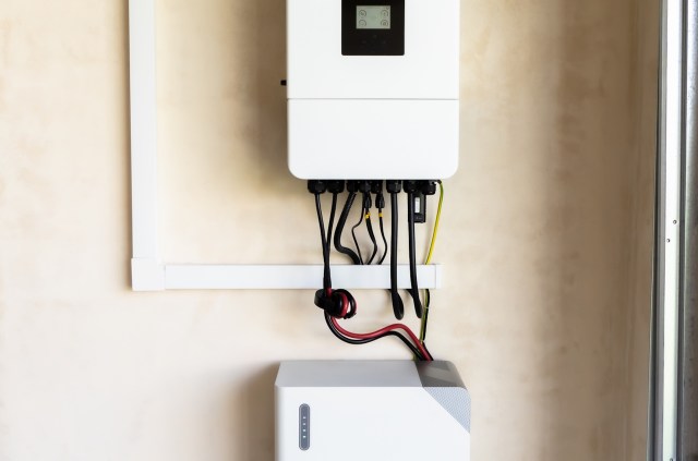 A wall-mounted energy storage system with connected cables.