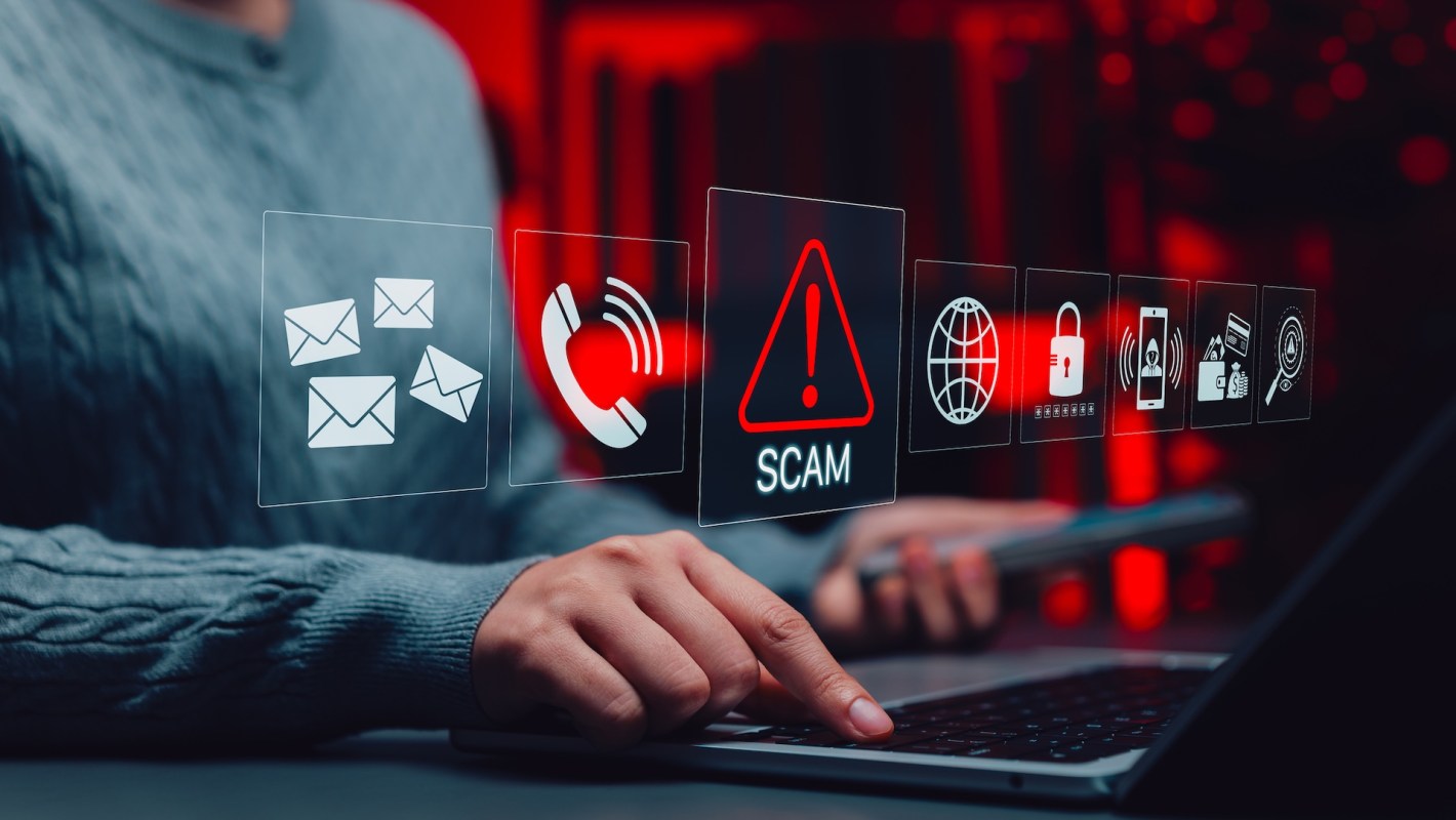A person interacts with a laptop displaying icons related to online scams and cybersecurity.