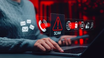 A person interacts with a laptop displaying icons related to online scams and cybersecurity.