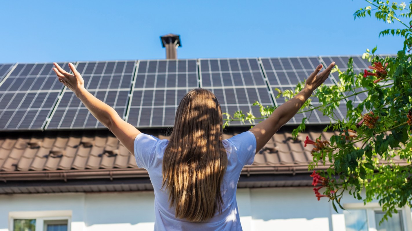A happy person standing in front of solar panels.