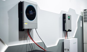 Two energy storage units mounted on a wall with visible wiring.
