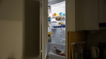 A refrigerator filled with various food items and containers, partially open in a kitchen setting.