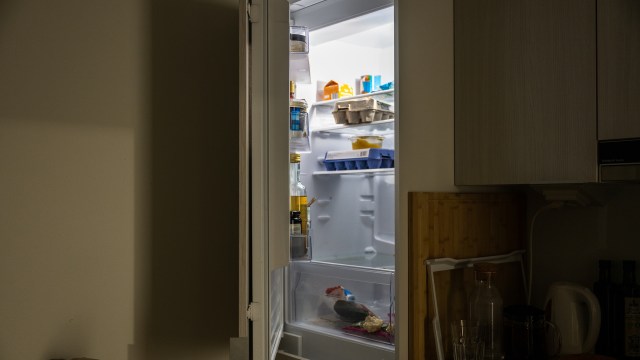 A refrigerator filled with various food items and containers, partially open in a kitchen setting.