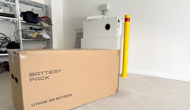 A cardboard box labeled "Battery Pack" in a garage with shelves and a yellow post.
