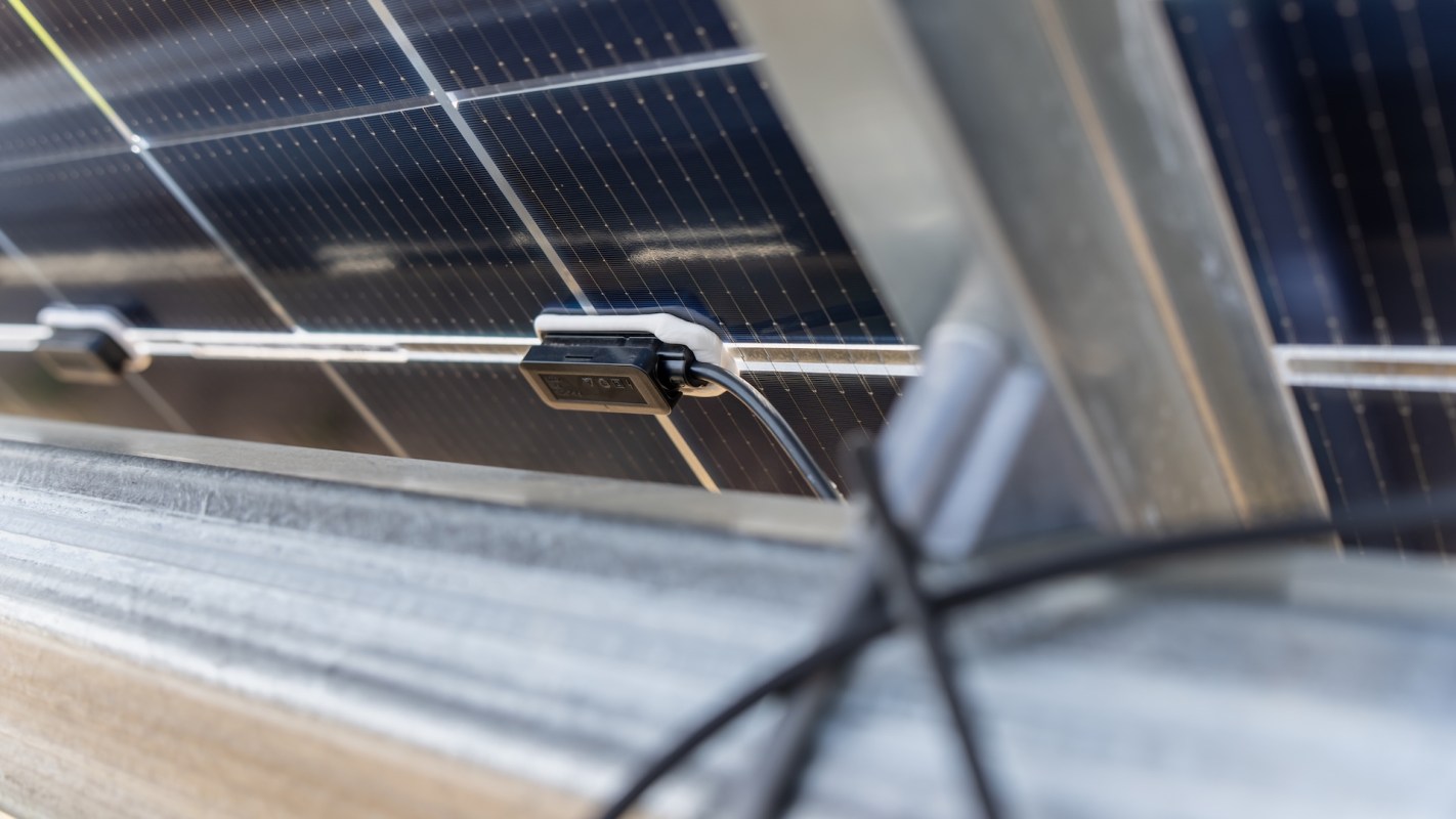 A solar panel with connecting wires and a junction box mounted on a metal frame.