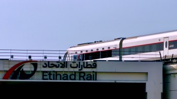 A train passing by the Etihad Rail station sign.