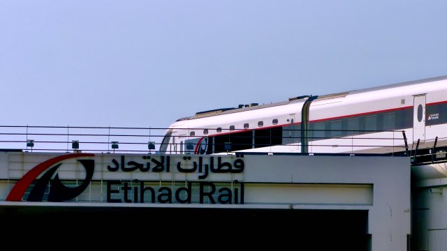 A train passing by the Etihad Rail station sign.