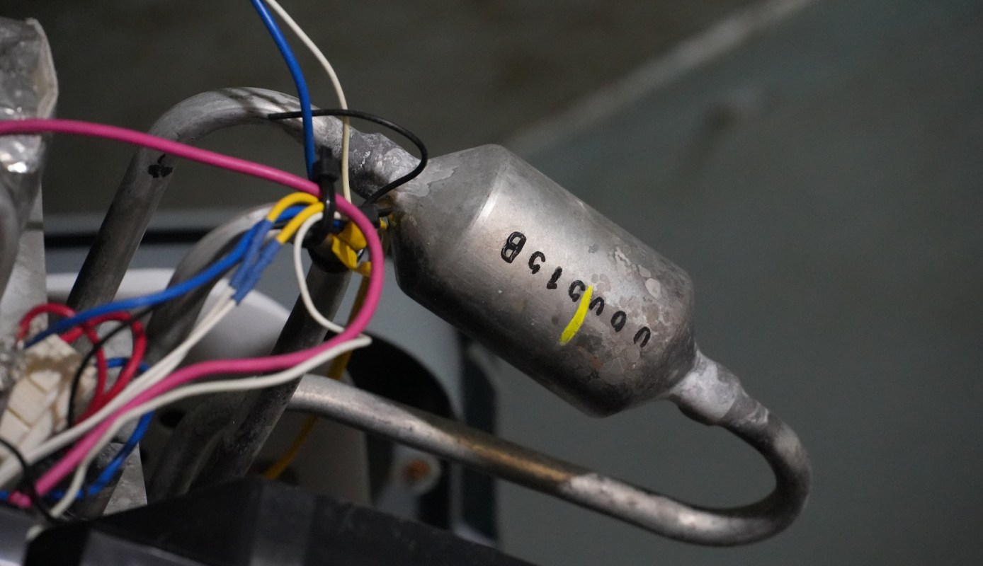A metal component with attached wires and visible markings.