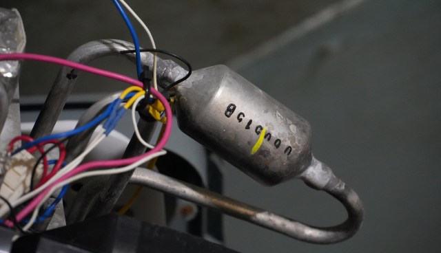 A metal component with attached wires and visible markings.