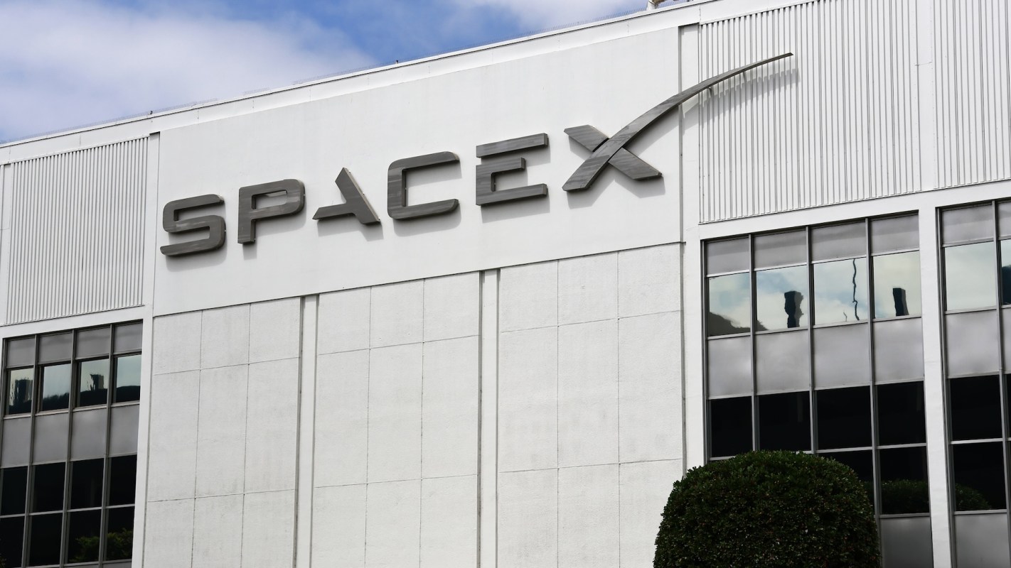 The SpaceX logo displayed on the exterior of a building.