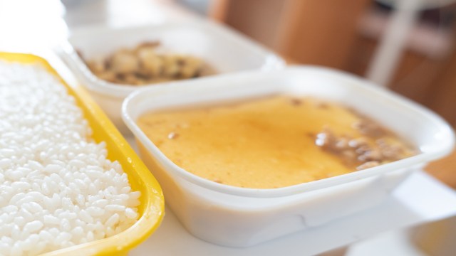 A tray containing rice and two food containers with different dishes.