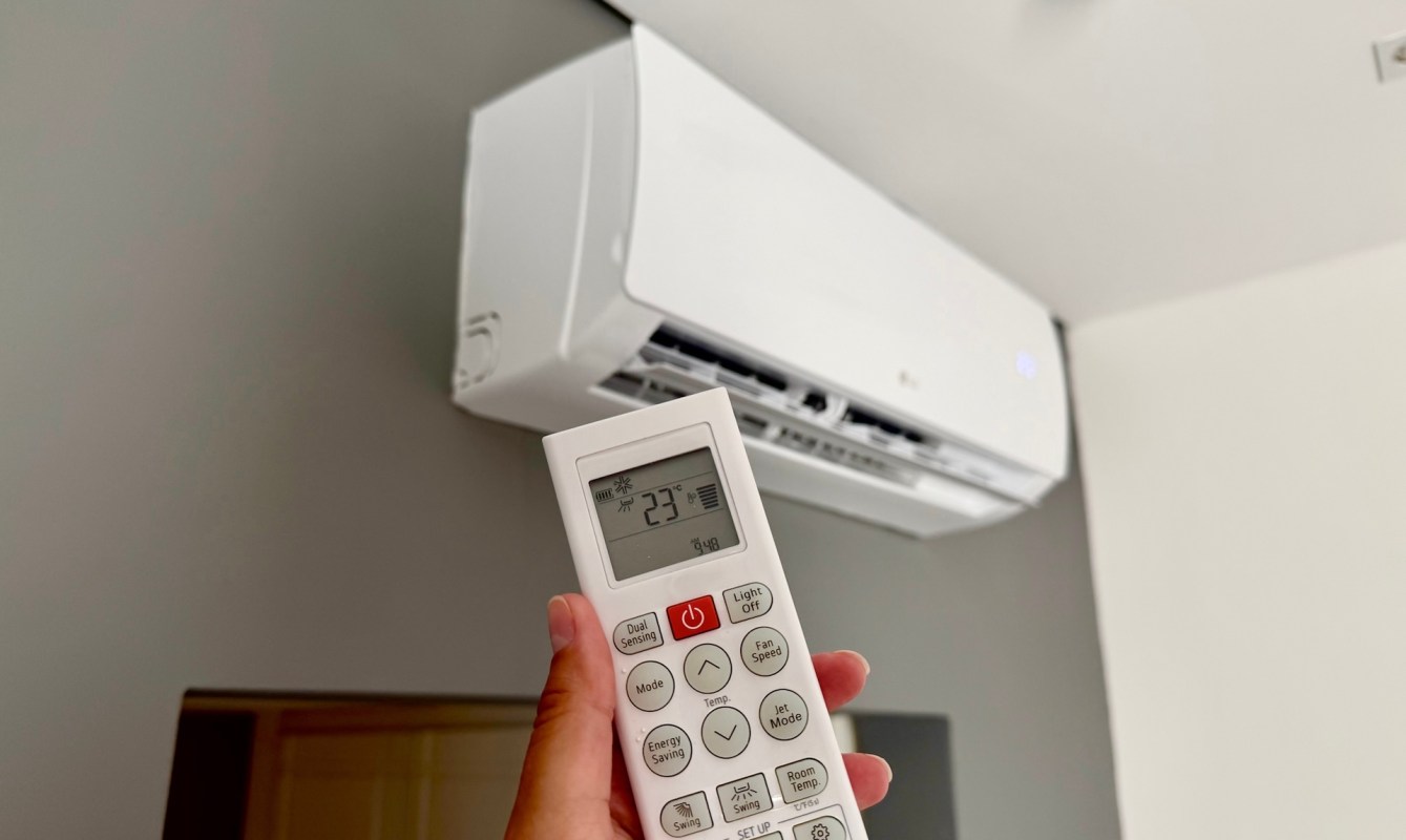 A person adjusting an AC unit's temperature.