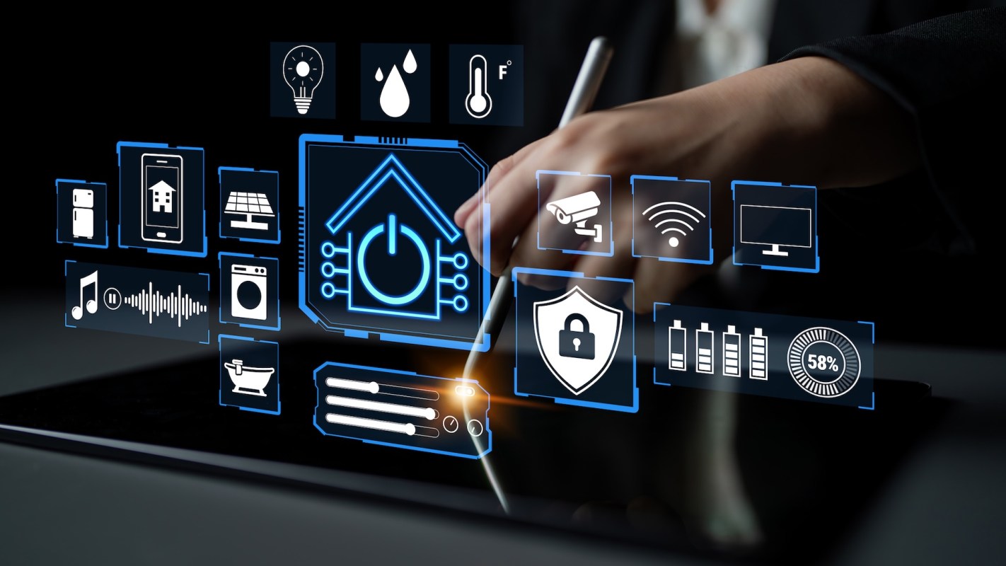 A hand holding a stylus interacts with a digital tablet displaying various smart home icons.
