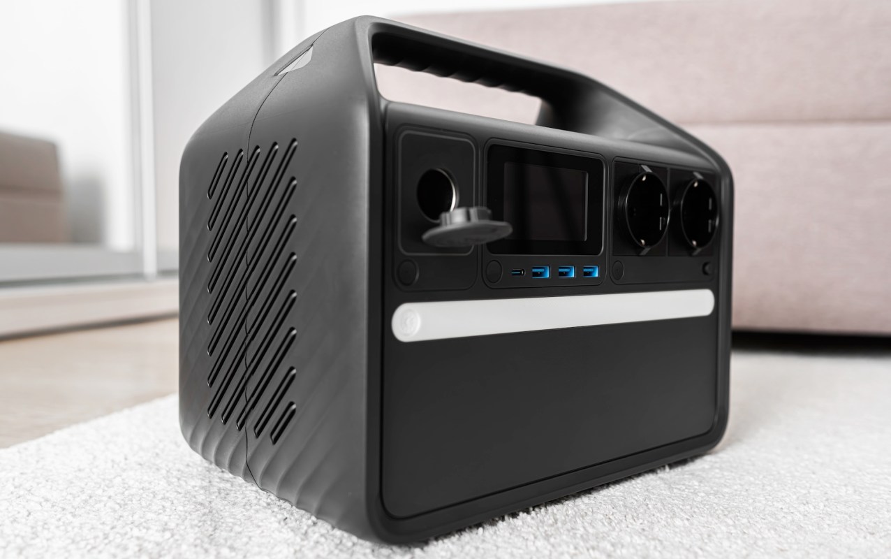 A portable power station with various ports and a digital display on a textured surface.