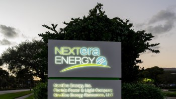 A sign for NextEra Energy with surrounding greenery during twilight.