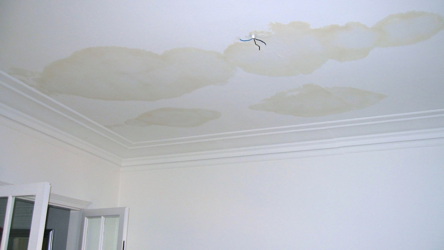 A ceiling with water damage stains and exposed wiring.