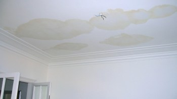 A ceiling with water damage stains and exposed wiring.