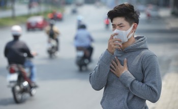 A man wearing a mask by a roadway.