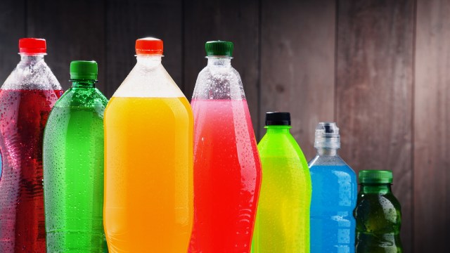 A variety of colorful beverage bottles with condensation against a wooden background.