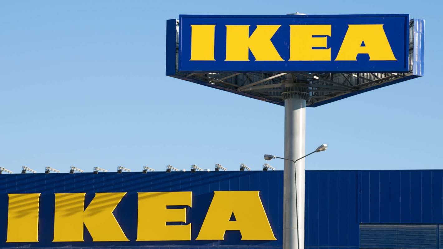 A large IKEA sign mounted on a tall pole against a clear blue sky.