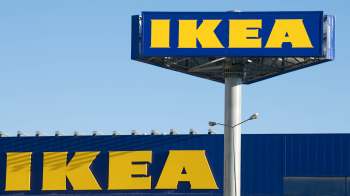 A large IKEA sign mounted on a tall pole against a clear blue sky.