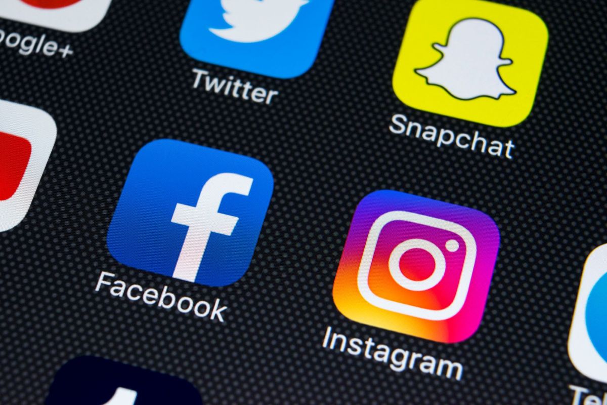 A close-up of various social media app icons (Facebook Instagram) on a smartphone screen.