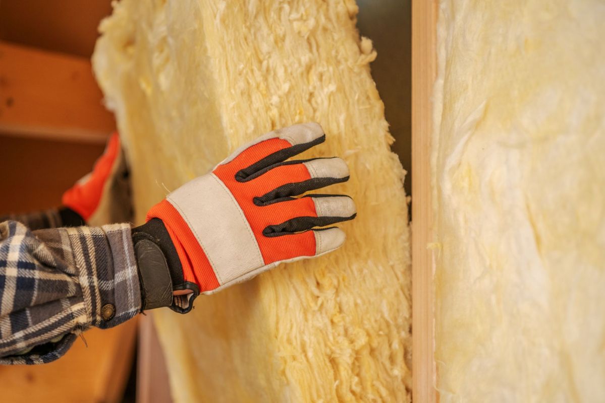 A worker adding insulation to a wall.