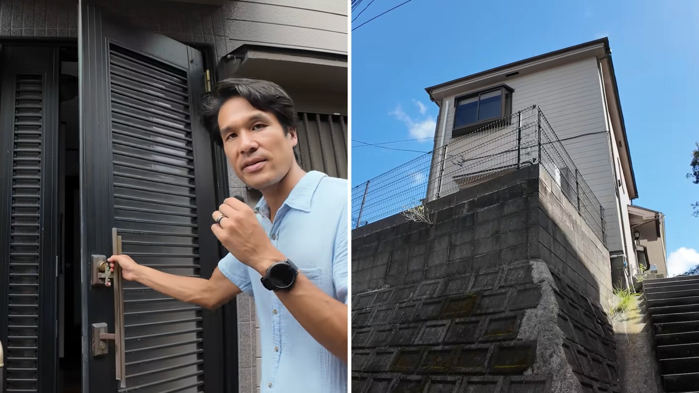 A person opens a front door with a modern design, with a house and blue sky visible in the background.