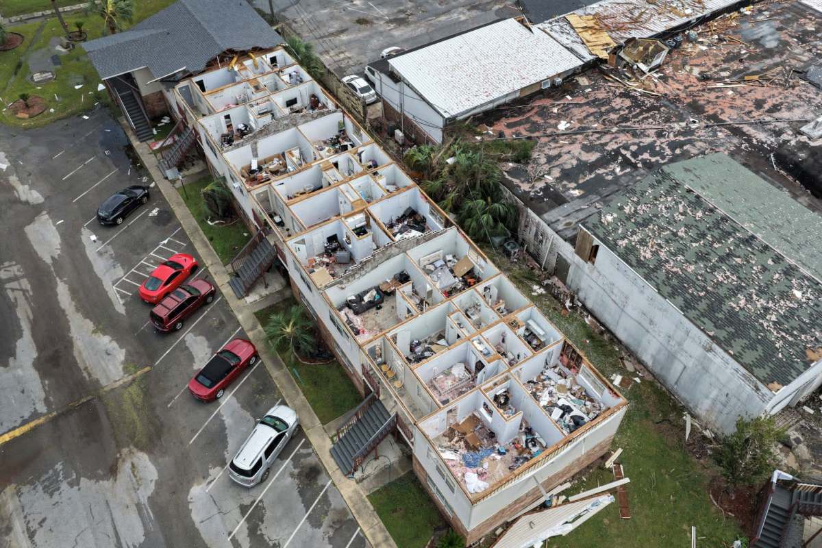 Aerial view of a damaged building from Hurricane Isaias, surrounded by parked cars in a parking lot.