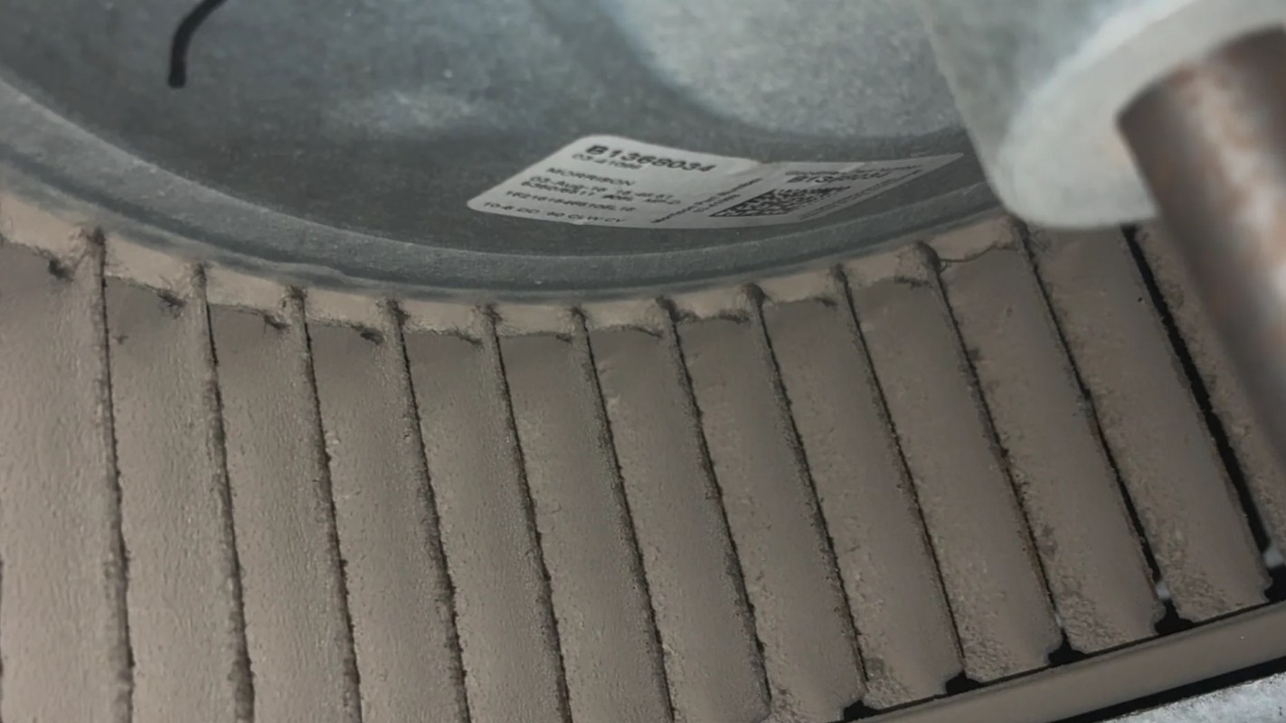 A close-up of a dusty machine component with grooves and a label attached.