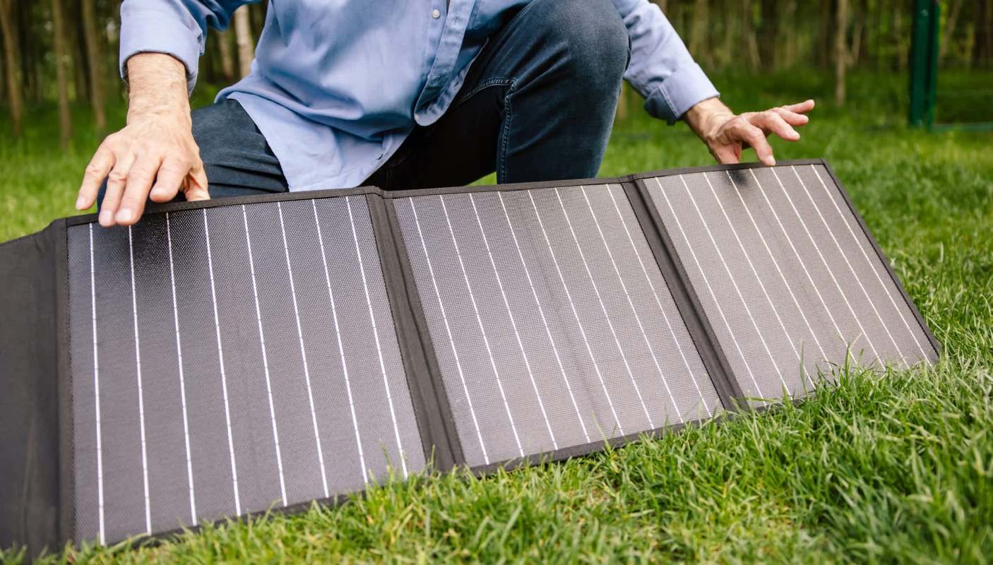 A person setting up a portable solar panel.