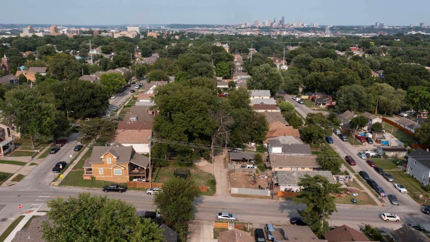 An aerial view of a residential neighborhood with numerous houses and trees, and Kansas City in the background.