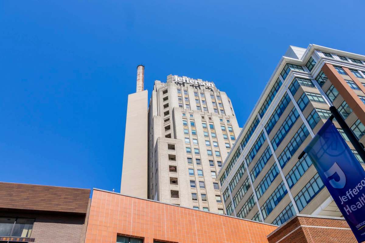 A view of the Jefferson Health building and adjacent structures under a clear blue sky.