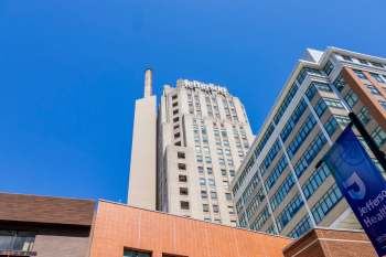 A view of the Jefferson Health building and adjacent structures under a clear blue sky.