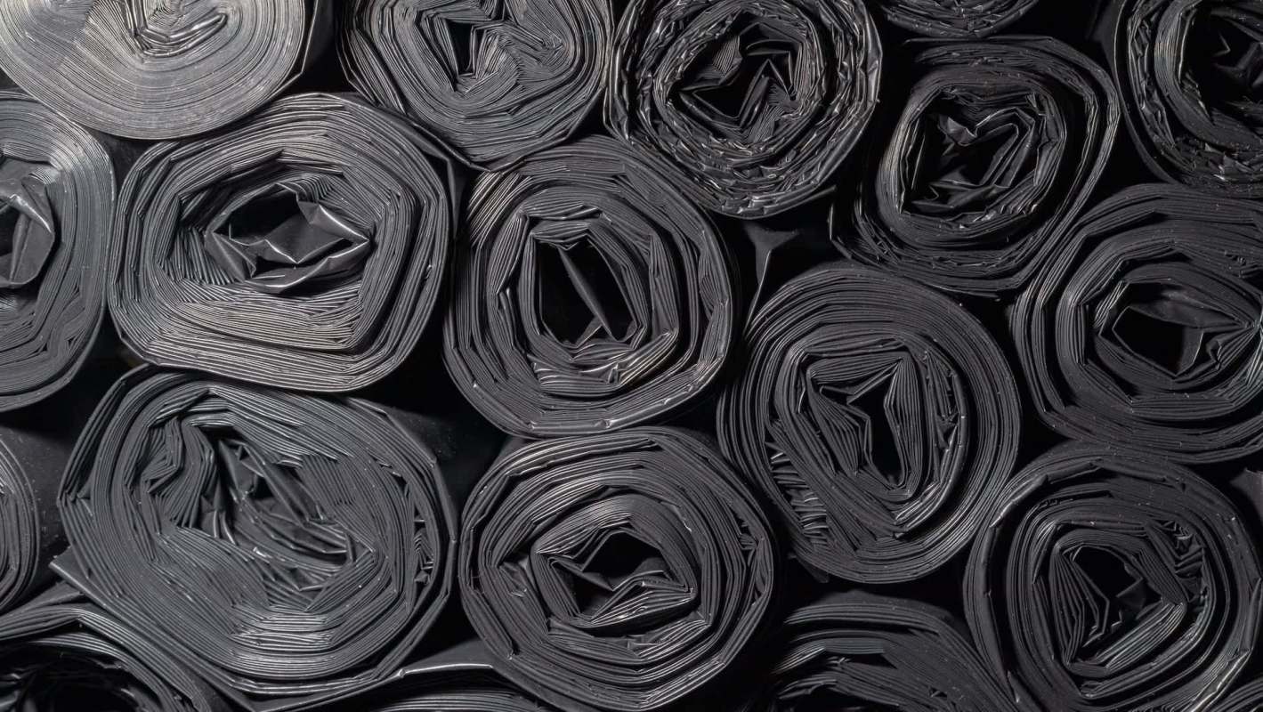 Rolled black plastic sheeting arranged in a pattern.