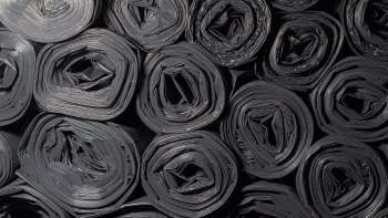 Rolled black plastic sheeting arranged in a pattern.