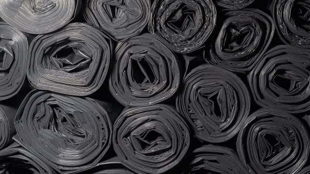 Rolled black plastic sheeting arranged in a pattern.