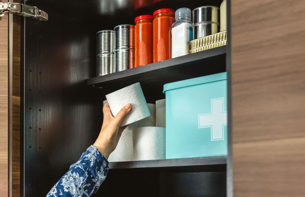 A person organizing a cabinet with emergency supplies.