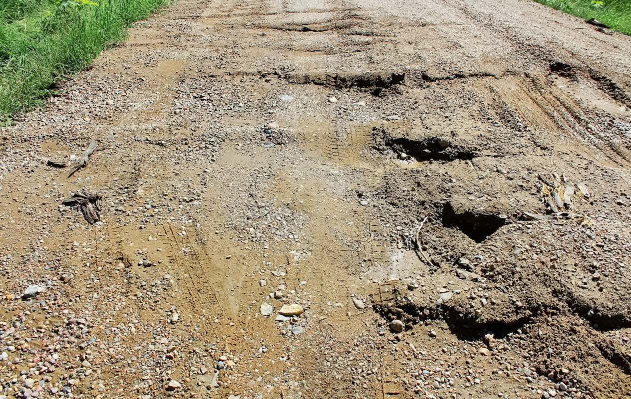 A dirt road with rough patches, rocks, and tire tracks.